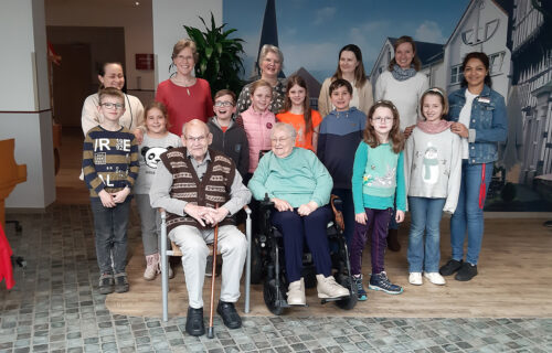 Gruppe von Jung und Alt, die zusammen in einem Gemeinschaftsraum posieren und lächeln.