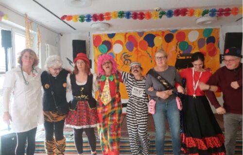 Menschen in bunten Kostümen feiern fröhlich Karneval in festlich dekoriertem Raum.