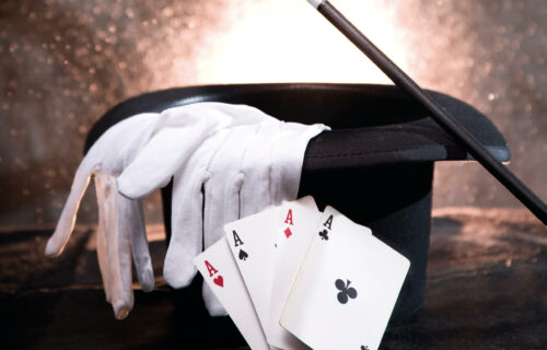 Zaubererhut, weißer Handschuh, Zauberstab und vier Asse, die Magie und Tricks symbolisieren.