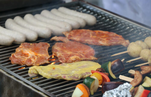 Grill mit Würstchen, mariniertem Fleisch und Gemüse-Spießen, ideal für sommerliche Barbecue-Partys.