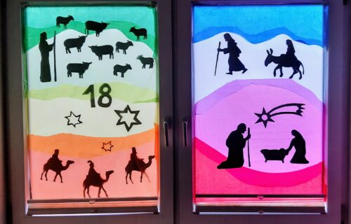 Weihnachtsfenster mit Krippenszenen, Hirten und Sternen aus buntem Papier am 18. Dezember. Festliche Dekoration.