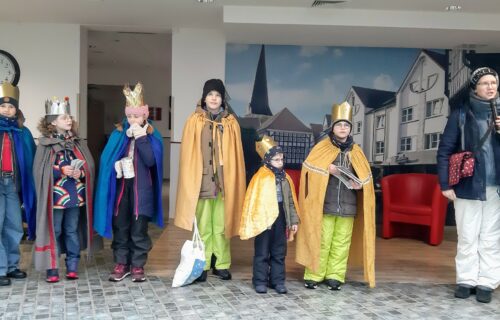Kinder in der traditionellen Sternsinger-Verkleidung stehen in einer Reihe und singen drinnen.